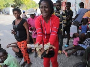 Rose Delpe cries as she shows money next to people displaced by gang war violence in Cite Soleil resting on the streets of Delmas neighbourhood after leaving Hugo Chaves square in Port-au-Prince, Haiti, Nov. 19, 2022.