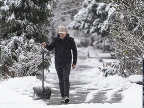 A man clears the sidewalk of snow in Vancouver on Dec. 18. Another storm is on the way this week just before the holidays.