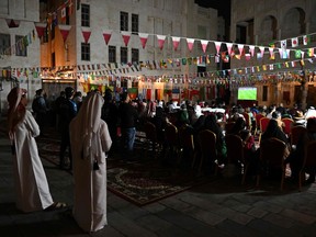 People watch the Qatar 2022 World Cup semi-final football match between France and Morocco on a screen set up in a courtyard in the souk in Doha on December 14, 2022. (Photo by Paul ELLIS / AFP)