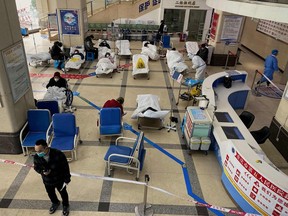 A man stands in front of a cordoned-off area, where COVID-19 patients lie on hospital beds, in the lobby of the Chongqing No. 5 People's Hospital in China's southwestern city of Chongqing on Dec. 23, 2022.