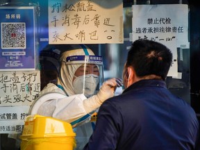 A medical worker in a protective suit collects a swab sample from a man at a nucleic acid testing site, as coronavirus disease (COVID-19) outbreaks continue in Shanghai, China, December 12, 2022.