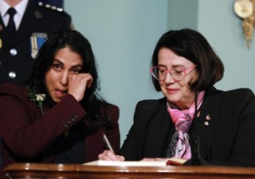 B.C. Attorney General Niki Sharma wipes away tears as she signs her name with Lt.-Gov Janet Austin on during the swearing-in ceremony at Government House in Victoria on Dec. 7, 2022.