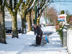 A man clears his sidewalk after a snowstorm hit Metro Vancouver in late November.