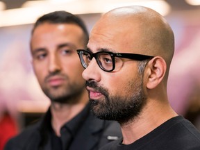 Mehran Seyed-Emami (left) listens while his brother Ramin speak to reporters after arriving from Iran at Vancouver International Airport on March, 8, 2018.