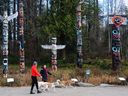 Dog walkers pass Stanley Park's totem poles.