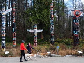 Dog walkers walk past the totem poles in Stanley Park.