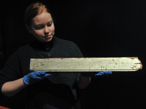 Mary Elizabeth Harrison, a curator at the Vancouver Maritime Museum with a piece of wood bearing the signature of Sewell Moody with the words "All Lost" that was recovered from a beach in Victoria in December 1875 following the wreck of the Pacific.