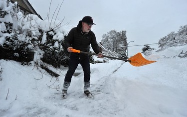 Vancouver residents clear sidewalks outside their homes on Dec. 20, 2022