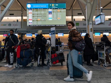 Eager travellers line up in various lines hoping to check in for their flights at Vancouver International Airport on Dec. 23, 2022.