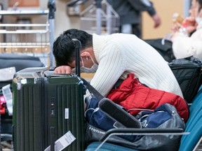 A man gets a cat nap at Vancouver International Airport as delays and cancelled flights cause havoc for holiday travellers on Dec. 23, 2022.
