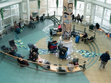 Passengers find a spot in the atrium of Vancouver International Airport as delays and cancelled flights cause havoc for holiday travellers on Dec. 23, 2022.