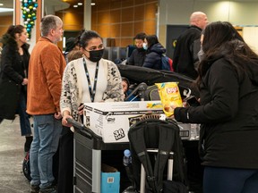 Vancouver International Airport staff hand out snacks and water to delayed passengers as weather delays and cancelled flights cause havoc for holiday travellers on Dec. 23, 2022.