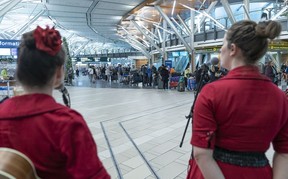 Singers entertain a long line of passengers waiting to rebook with Air Canada at Vancouver International Airport as delays and cancelled flights cause havoc for holiday travellers on Dec. 23, 2022.