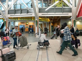 Passengers wait in a line that stretches into the international departures hall to rebook with Air Canada at Vancouver International Airport on Friday.