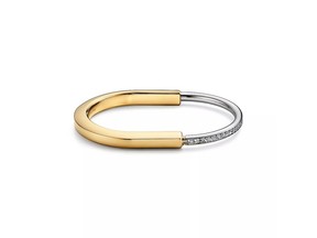 A simply chic statement piece, this Tiffany Lock Bangle from American luxury jewelry brand Tiffany & Co. is crafted from 18-karat yellow and white gold, and features a row of dazzling pavé-set diamonds.