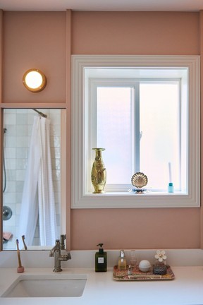 Mixing up metals with a brass sconce and brushed stainless faucet in this bathroom designed by Studio Roslyn.