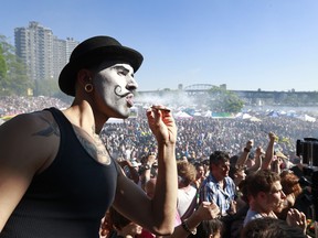 A man sports a painted face as he smokes marijuana as thousands of people gather at 4/20 celebrations on April 20, 2016 at Sunset Beach in Vancouver.