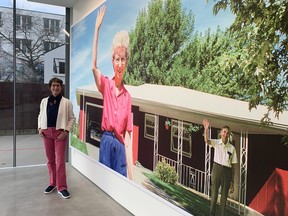 Deanna Dyckman in front of a mural depicting her photograph waving with her mother and father waving at her home in Sioux City, Iowa, August 1991. Leaving and Waving to April 22nd.
