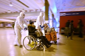 Workers wearing protective masks and suits help a Chinese traveler leaving the arrivals hall of Rome Fiumicino International Airport near Rome on December 29, 2022 after being tested for the COVID-19 coronavirus.