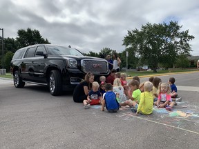 The entire group of children in this photo are not in the sightline of the driver of this large SUV.