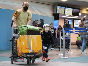 A man and young boy who arrived on a Cathay Pacific flight from Hong Kong walk together at Vancouver International Airport in Richmond, B.C. on Wednesday, January 4, 2023. Starting Thursday, Canada will require travellers from China, Hong Kong and Macau to have a recent negative COVID-19 test result.
