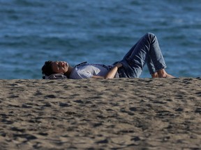 A man enjoys the sun in front of the sea during unseasonably warm temperatures in Malaga, southern Spain, January 4, 2023. REUTERS/Jon Nazca