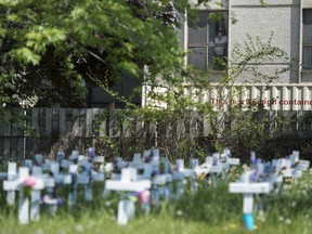 A man looks out the window at the Camilla Care Community centre overlooking crosses marking the deaths of multiple people that occurred during the COVID-19 pandemic in Mississauga, Ont., on May 26, 2020.