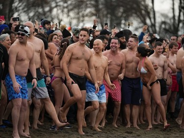 People gather before plunging into English Bay during the Polar Bear Swim, in Vancouver, B.C., Sunday, Jan. 1, 2023. This year's event was the first since 2020 after the past two years were cancelled due to the COVID-19 pandemic. According to the City of Vancouver the initial swim was in 1920 when approximately 10 swimmers participated.