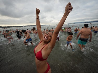 A woman reacts as she runs out of the water after plunging into English Bay during the Polar Bear Swim, in Vancouver, B.C., Sunday, Jan. 1, 2023.