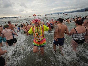 A person dressed in a costume runs out of the water as others plunge into English Bay during the Polar Bear Swim, in Vancouver, B.C., Sunday, Jan. 1, 2023. This year's event was the first since 2020 after the past two years were cancelled due to the COVID-19 pandemic. According to the City of Vancouver the initial swim was in 1920 when approximately 10 swimmers participated.