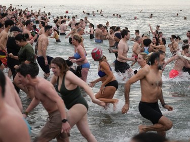 People take part in the Polar Bear Swim at English Bay, in Vancouver, B.C., Sunday, Jan. 1, 2023. This year's event was the first since 2020 after the past two years were cancelled due to the COVID-19 pandemic. According to the City of Vancouver the initial swim was in 1920 when approximately 10 swimmers participated.