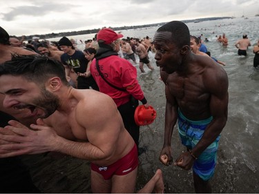 People react as they run out of the water after plunging into English Bay during the Polar Bear Swim, in Vancouver, B.C., Sunday, Jan. 1, 2023. This year's event was the first since 2020 after the past two years were cancelled due to the COVID-19 pandemic. According to the City of Vancouver the initial swim was in 1920 when approximately 10 swimmers participated.