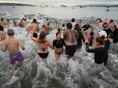 People plunge into English Bay during the Polar Bear Swim, in Vancouver, B.C., Sunday, Jan. 1, 2023. This year's event was the first since 2020 after the past two years were cancelled due to the COVID-19 pandemic. According to the City of Vancouver the initial swim was in 1920 when approximately 10 swimmers participated.