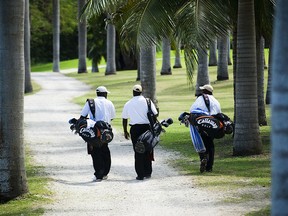 Three caddies head for the green at Half Moon golf course.