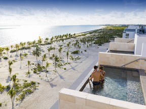 A couple enjoys the view from their plunge pool suite at Majestic Elegance Costa Mujeres.