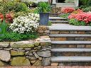Stone wall, steps and a planter in a colourful, landscaped garden.