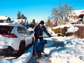 Vancouver residents clear the sidewalks on Sunday morning after an overnight snowstorm.