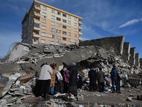 Families stand beside the rubble of collapsed buildings in Kahramanmaras, Turkey on February 7, 2023, a day after a 7.8-magnitude earthquake struck southeast Turkey (Photo by OZAN KOSE/AFP).