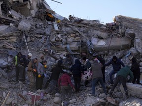 People carry a dead body from a collapsed building in Kahramanmaras, southern Turkey,