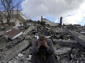 A woman sits on the rubble as emergency rescue teams search for people under the remains of destroyed buildings in Nurdagi town on the outskirts of Osmaniye city southern Turkey, Tuesday, Feb. 7, 2023. The earthquake that ravaged Turkey and Syria this week offers both lessons and warnings for people in British Columbia as images emerge of the human devastation and costly damage, Canadian seismology experts say.