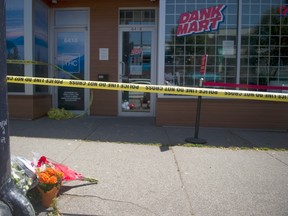 Police tape blocks the sidewalk where flowers were laid out in front of the Dank Mart on Main Street after Amin Shahin Shakur was suddenly and violently killed on July 13, 2020.