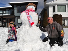 Jason Phillips and his neighbour work on a snowman in the front yard of his North Vancouver home on Sunday.