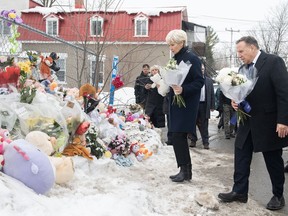 Quebec Premier Francois Legault and wife Isabelle Brais bring flowers to the site of a daycare centre in Laval, Que., Thursday, Feb. 9, 2023, where a bus crashed into the building killing two children.