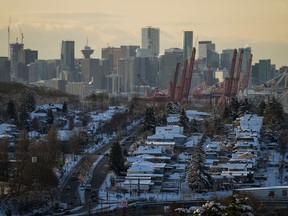 Houses are covered with snow as the downtown skyline is seen in the distance, in Vancouver, on Wednesday, December 21, 2022. The British Columbia Real Estate Association says the chill across the province's real estate sector will drag on through 2023, but it calls for a strong rebound next year.