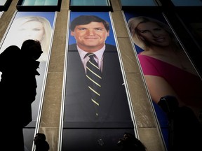FILE PHOTO: People pass by a promo of Fox News host Tucker Carlson on the News Corporation building in New York, U.S., March 13, 2019. REUTERS/Brendan McDermid