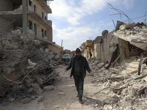 A man walks past collapsed buildings following a devastating earthquake in the town of Jinderis, Aleppo province, Syria, Tuesday, Feb. 14, 2023. The death toll from the earthquakes of Feb. 6, that struck Turkey and northern Syria is still climbing.