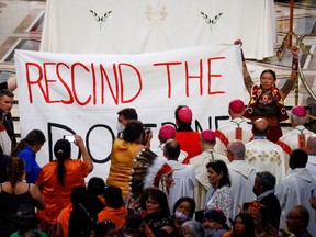 Indigenous people hold a banner opposing the Doctrine of Discovery as Pope Francis presides over a mass at the Shrine of Sainte-Anne-de-Beaupre, one of the oldest and most popular pilgrimage sites in North America, in Sainte-Anne-de-Beaupre in Quebec on July 28, 2022. The banner reads: "Rescind the doctrine". On March 30, 2023, the Vatican issued a statement rejecting the doctrine.