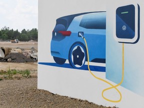 A board showing an electric Volkswagen car at a charging station is pictured in front of the construction site of Volkswagen's battery cell plant in Salzgitter, Germany, in 2022.