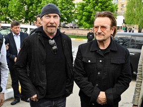 Bono (R) (Paul David Hewson), activist and front man of the Irish rock band U2 and guitarist David Howell Evans aka 'The Edge' (L) visits the site of a mass grave by the Church of St. Andrew Pervozvannoho All Saints in the Ukrainian town of Bucha, near Kyiv on May 8, 2022. (Photo by Genya SAVILOV / AFP)