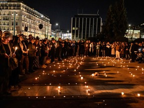 People hold candles and black balloons during a silent demonstration in front of the Greek Parliament in Athens, on March 3, 2023, as parallel demonstrations take place, following the deadly accident near the city of Larissa, where 57 people, mainly students lost their lives. (Photo by Louisa GOULIAMAKI / AFP)